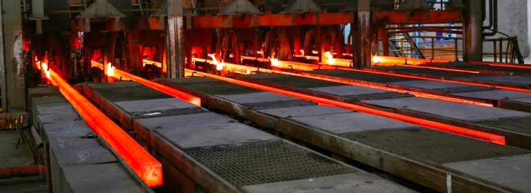 Maquinaria industrial sacando barras al rojo vivo de metales ferrosos
