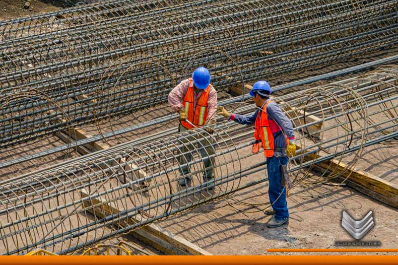 Trabajadores de la construcción armando una estructura con acero de refuerzo en medio de una obra