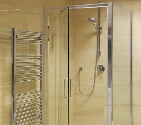 Vista frontal de una puerta y vidrio para baño que cerca el área destinada a la regadera, a la izquierda hay una estructura metálica para colocar las toallas